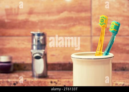 Spazzolini colorati nella tazza del lavandino del bagno. Ambienti sanitari e igienici Foto Stock