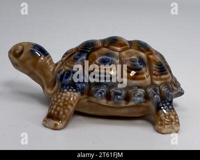 Una foto ravvicinata di una statuetta di tartaruga in ceramica verde su sfondo bianco Foto Stock
