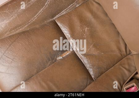 primo piano del sedile in pelle usato e strappato, del sedile beige con usura, inclusi graffi, pieghe e graffi, riparazioni e servizi Foto Stock