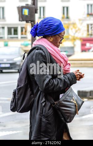 Donna nera francese-africana ben vestita che controlla gli oggetti in mano - Paris 20, Francia. Foto Stock