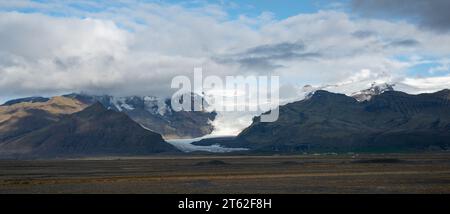 Un paesaggio invernale panoramico caratterizzato da una serie di montagne innevate contro un cielo parzialmente nuvoloso. Foto Stock