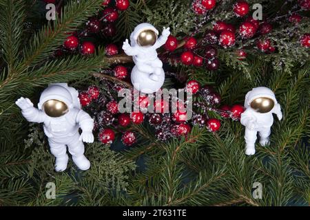 composizione di cosmonauti bianchi nel cuore dei rami di abete e di un ramo holly con le sue bacche rosse. Foto Stock