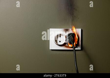 presa elettrica a muro bruciata con il cavo dell'apparecchio collegato per evitare cortocircuiti all'interno dell'abitazione. concetto di sicurezza antincendio e sovraccarico di potenza a casa Foto Stock