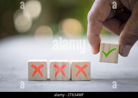 Lista di controllo dei blocchi di legno e icona del segno di spunta verde con la mano sullo sfondo della tabella. Informazioni sulla programmazione degli appuntamenti per la firma dell'attività aziendale. Posto da uomo d'affari Foto Stock