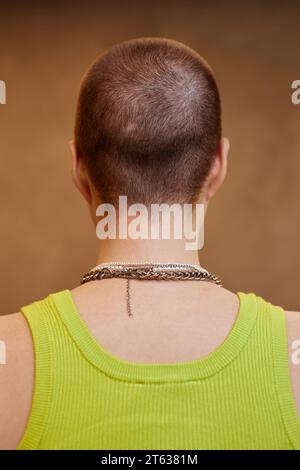 Vista posteriore di una giovane donna irriconoscibile, con il buzzcut rivolto lontano dalla telecamera in studio Foto Stock