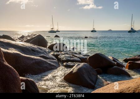 Rocce di granito e barche a vela ad Anse Lazio, spiaggia panoramica nell'isola di Praslin, Seychelles Foto Stock
