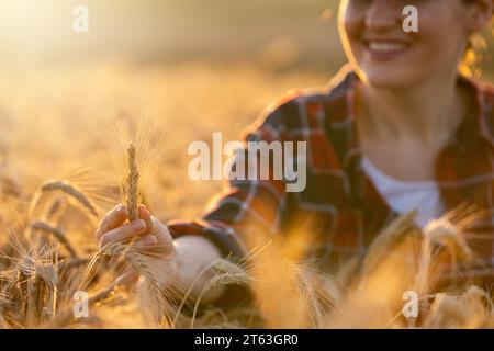 La contadina tocca le orecchie del grano su un campo agricolo. Foto Stock