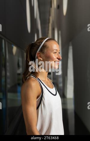 Foto di una donna attiva scattata in una canotta bianca che posa Foto Stock