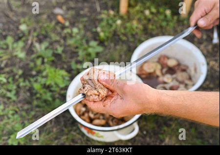 un pezzo di carne per un barbecue è appeso su uno spiedino. preparazione per cucinare lo shish kebab. Foto Stock