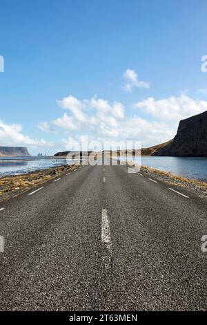 Prospettiva in diminuzione di asfalto strada vuota con segnaletica stradale che passa attraverso il lago panoramico contro il cielo in Islanda Foto Stock