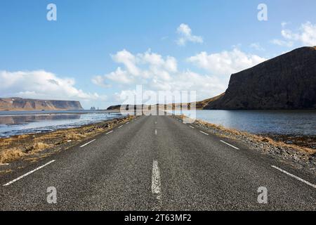 Prospettiva in diminuzione di asfalto strada vuota con segnaletica stradale che passa attraverso il lago panoramico contro il cielo in Islanda Foto Stock