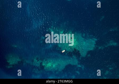 Dall'alto, vista aerea con droni di una barca a vela che naviga attraverso acque turchesi Foto Stock