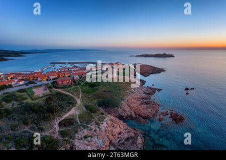 Vista dall'alto del villaggio di Castelsardo con la sua torre storica, il porticciolo e la costa circostante durante il tramonto in Sardegna Foto Stock