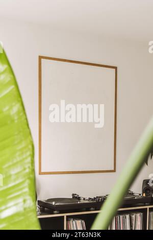 Telaio vuoto montato su parete bianca con giradischi vintage in vinile nella casa moderna Foto Stock