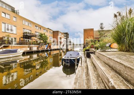 Piccole barche ormeggiate su un canale tranquillo di fronte agli edifici residenziali sotto il cielo nuvoloso della città durante il giorno Foto Stock
