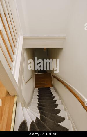 Vista ad alto angolo delle scale vuote con tappeto bianco e nero nella casa contemporanea Foto Stock