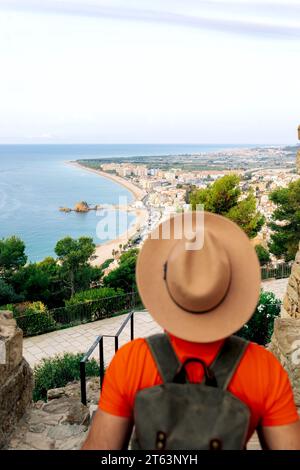 Vista ad alto angolo dell'uomo turistico da dietro con cappello a Barcellona guardando la vasta costa della spiaggia da un alto punto panoramico. Foto Stock