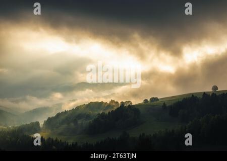 Paesaggio montuoso nebbioso autunnale con raggi del sole mattutino che brillano tra le nuvole. La regione di Orava in Slovacchia, Europa. Foto Stock