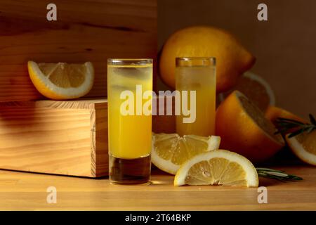Liquore tradizionale al limone limoncello e agrumi freschi su un tavolo di legno. Foto Stock