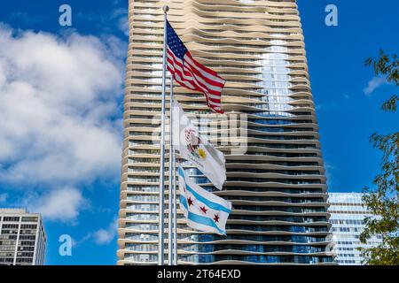 La bandiera americana, la bandiera dello stato dell'Illinois e la bandiera della città di Chicago sventolano davanti all'Aqua Tower a Chicago, Illinois, Stati Uniti. Foto Stock