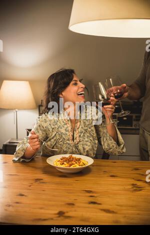 Donna che mangia un piatto di tagliatelle al Ragu bolognese in un'accogliente sala da pranzo. Foto Stock