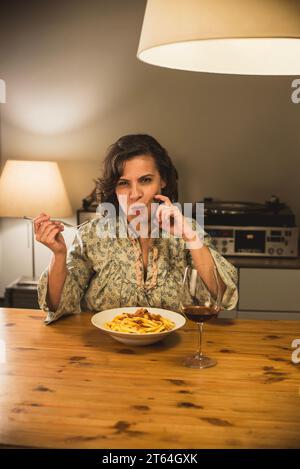 Donna che mangia un piatto di tagliatelle al Ragu bolognese in un'accogliente sala da pranzo. Foto Stock