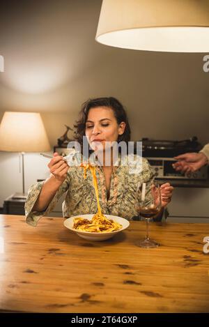 Donna che mangia un piatto di tagliatelle al Ragu bolognese in un'accogliente sala da pranzo. Foto Stock