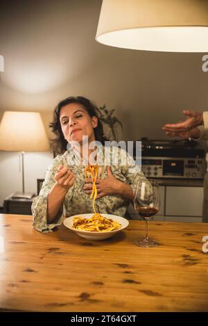 Donna che mangia un piatto di tagliatelle al Ragu bolognese in un'accogliente sala da pranzo. Foto Stock