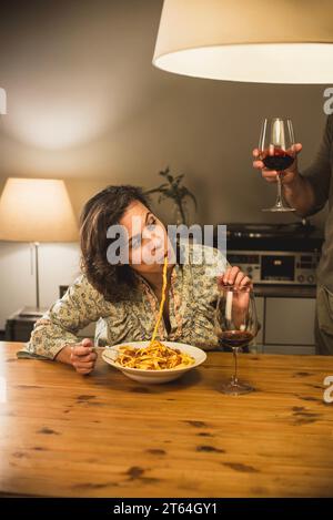 Donna che mangia un piatto di tagliatelle al Ragu bolognese in un'accogliente sala da pranzo. Foto Stock