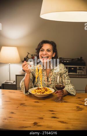 Donna che mangia un piatto di tagliatelle al Ragu bolognese in un'accogliente sala da pranzo. Foto Stock