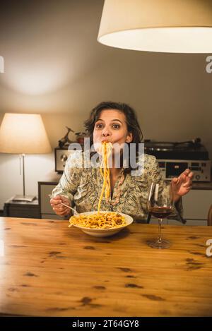 Donna che mangia un piatto di tagliatelle al Ragu bolognese in un'accogliente sala da pranzo. Foto Stock