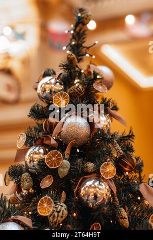 Dettagli magici. Stagione invernale alla vigilia delle vacanze. Creativo e interessante albero di Natale decorato con arance secche, mandarini, coni di pino e glitte dorate Foto Stock