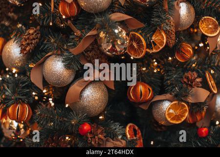 Decorazioni e atmosfera per le vacanze invernali. Mandarini secchi, arance, coni di pino palle natalizie appese ai rami dell'albero di Natale. Accogliente inverno de Foto Stock