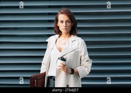 Donna d'affari sicura di sé con i capelli di zenzero. Uomo d'affari di mezza età che indossa abiti eleganti con una cartella in pelle. Foto Stock