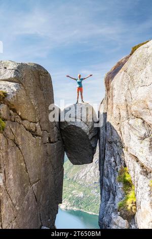 Donna in piedi su Kjeragbolten, incastrata roccia sopra il Lysefjord, Kjerag, Lysebotn, Rogaland, Norvegia Foto Stock