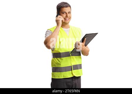 Assistente stradale in un giubbotto riflettente con in mano un documento ed effettuando una telefonata isolata su sfondo bianco Foto Stock