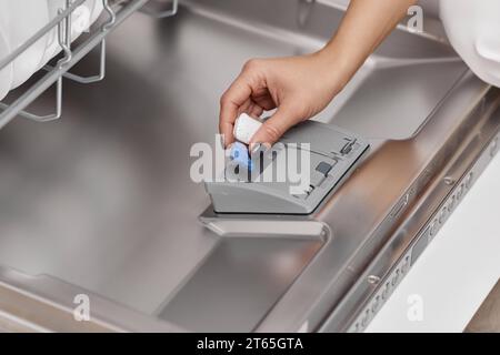 la mano femminile consente di aprire la lavastoviglie automatica incorporata. Primo piano Foto Stock