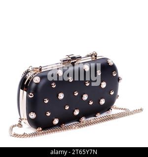 Pochette a catena lunga nera moderna e glamour da donna, decorata con rivetti in metallo oro e perle isolati su uno sfondo bianco isolato su un'erba bianca Foto Stock