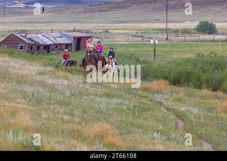 La tua famiglia è guidata da un'escursione a cavallo attraverso i campi del Terry Bison Ranch vicino a Cheyenne, Wyoming Foto Stock