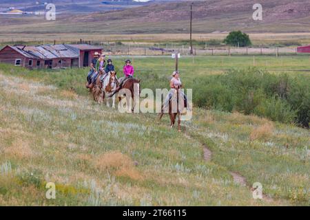 La tua famiglia è guidata da un'escursione a cavallo attraverso i campi del Terry Bison Ranch vicino a Cheyenne, Wyoming Foto Stock