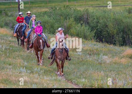 La tua famiglia è guidata da un'escursione a cavallo attraverso i campi del Terry Bison Ranch vicino a Cheyenne, Wyoming Foto Stock