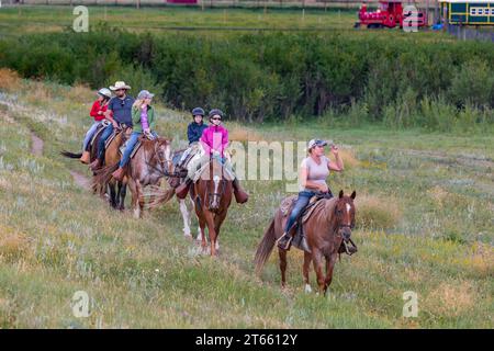 La tua famiglia è guidata da un'escursione a cavallo attraverso i campi del Terry Bison Ranch vicino a Cheyenne, Wyoming Foto Stock