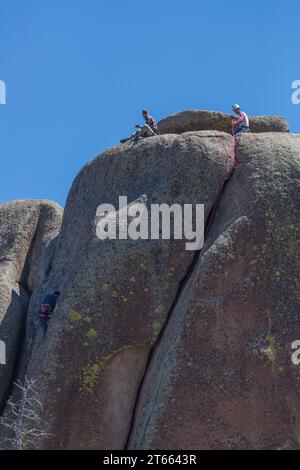 Uomini arrampicate su un grande masso di granito nella Vedauwoo Recreation area of Medicine Bow National Forest, Wyoming Foto Stock
