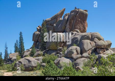 Uomini arrampicate su un grande masso di granito nella Vedauwoo Recreation area of Medicine Bow National Forest, Wyoming Foto Stock