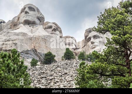 Busti di granito scolpiti di George Washington, Thomas Jefferson, Theodore Teddy Roosevelt e Abraham Lincoln incorniciati da alberi sul Monte Rushmore Foto Stock