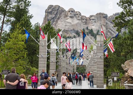 I turisti ammirano le sust di George Washington, Thomas Jefferson, Theodore Teddy Roosevelt e Abraham Lincoln sopra la Avenue of Flags al Mt. Rushmore Foto Stock