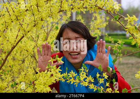 Contea di Luannan, Cina - 8 aprile 2017: Le signore scattano foto di fronte ai fiori di Forsythia nel parco, nella contea di Luannan, nella provincia di Hebei, in Cina. Foto Stock