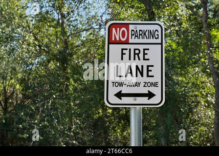 Primo piano con segnaletica Fire Lane e nessun parcheggio isolato con uno sfondo di tettoia di alberi e spazio fotocopie. Foto Stock