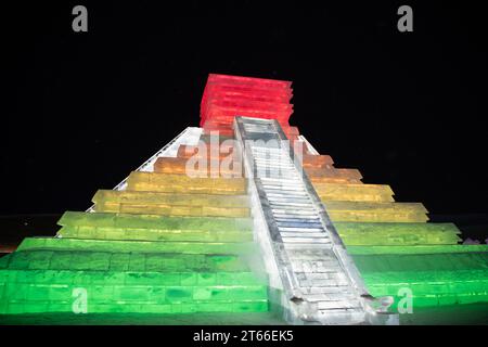 HARBIN, CINA - 1° gennaio 2022: Costruzione di ghiaccio a forma di piramide messicana. Harbin International Ice and Snow Festival. I turisti sono in visita. Loca Foto Stock