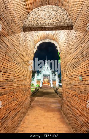 Alto, stretto, ad arco, corto tunnel, fiancheggiato da mattoni rossi, che conduce verso la porta di ingresso di ornati, tempio costruito in legno di teak, con facciata decorativa in argento e. Foto Stock